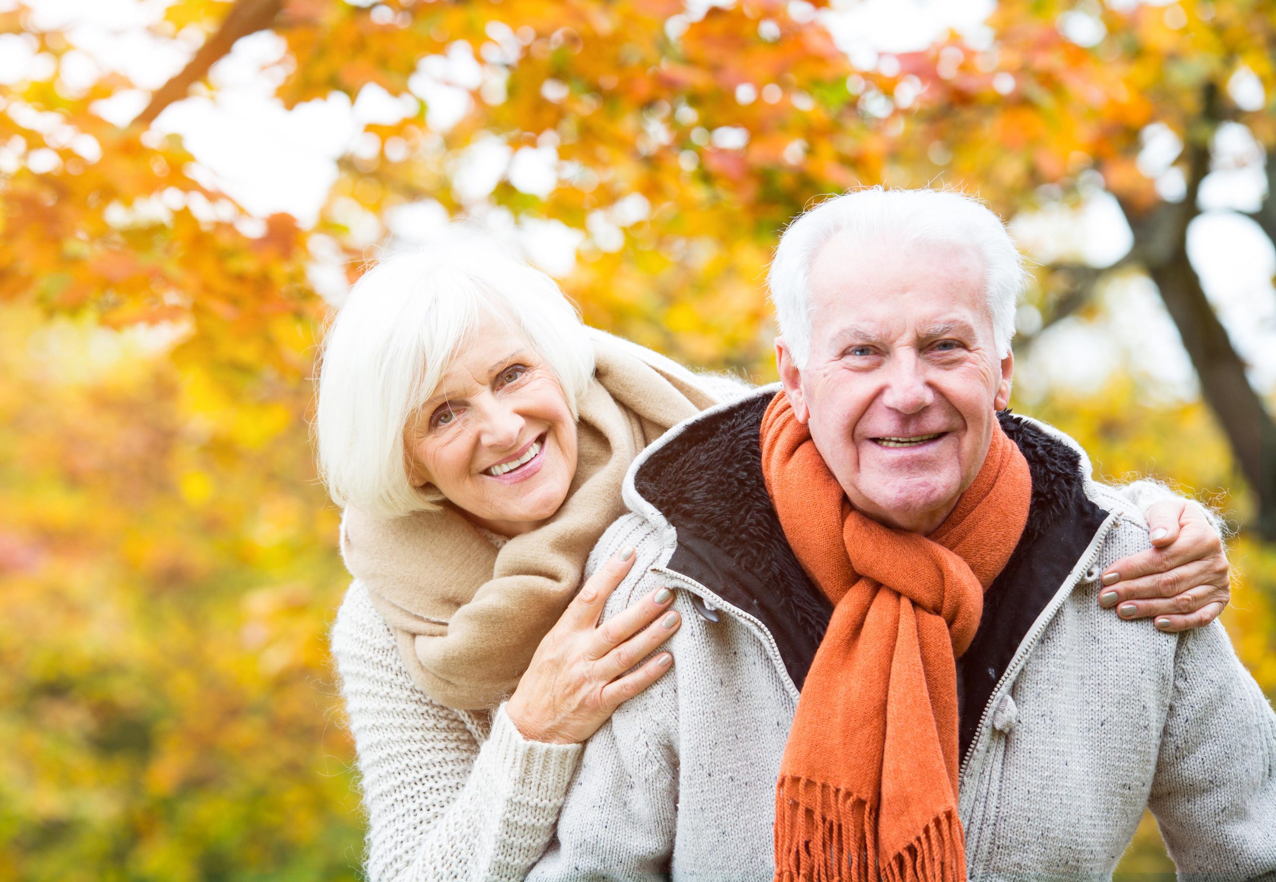 Happy senior couple outside with Autumn trees in the background